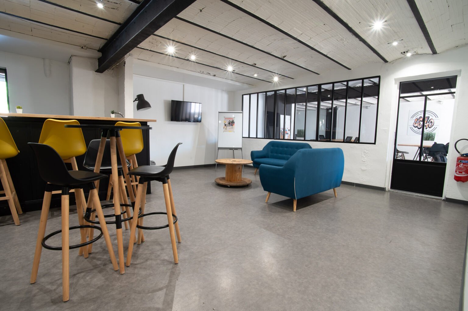 Espace détente du Bureau Le 40 à Marseille : bar, tabourets jaunes et fauteuils bleus