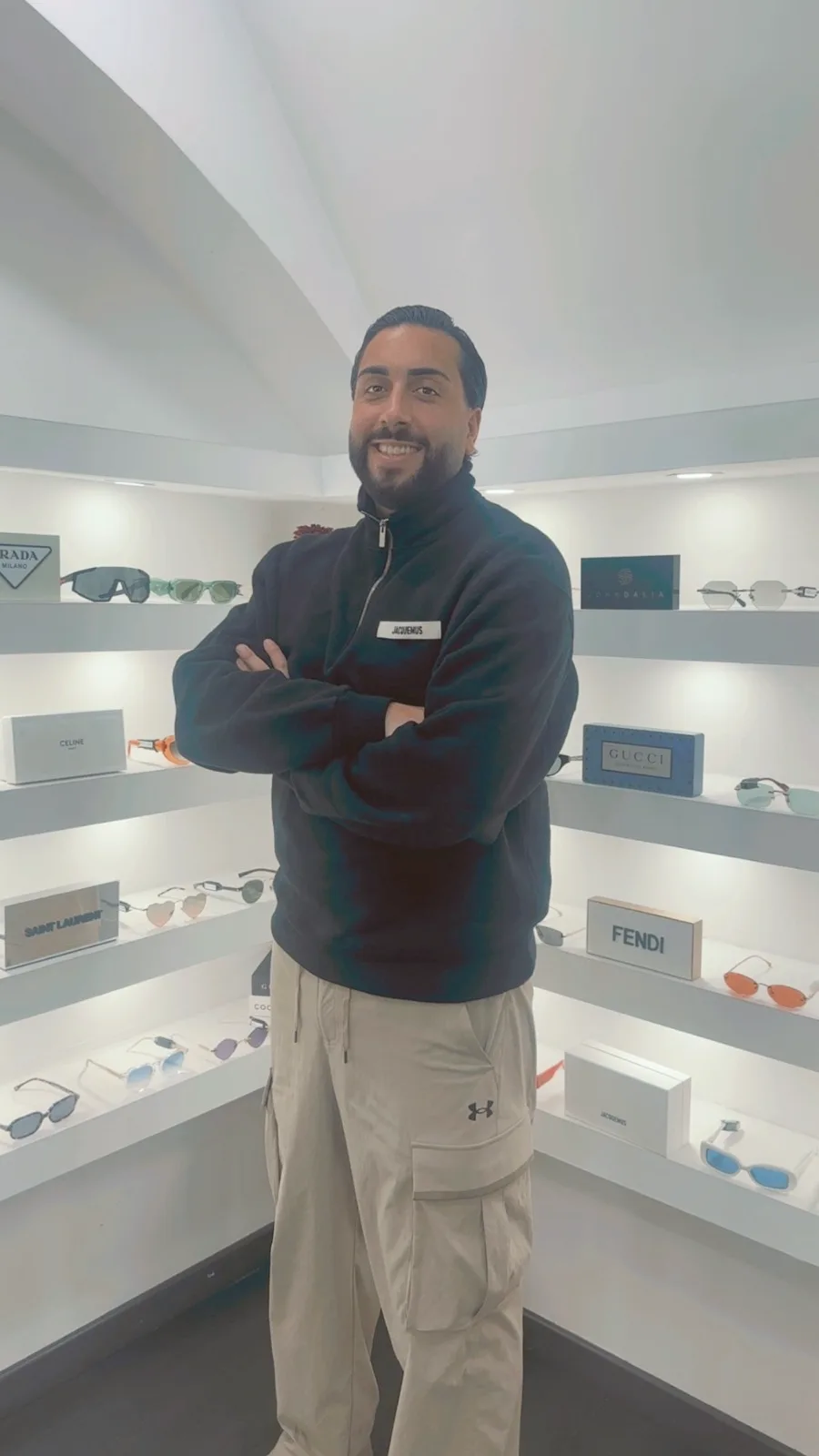 Rudy, cofondateur de J&J Optical, devant un mur de lunettes de grandes maisons